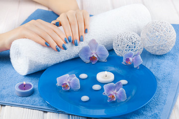 beautiful blue manicure with orchid and towel on the white wooden table. spa