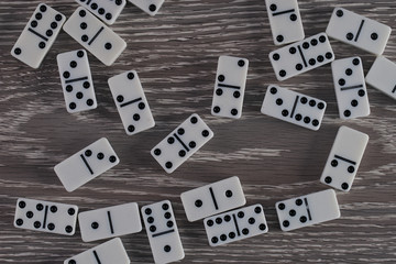 White domino play pieces on wooden table. Top view
