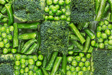 Fresh frozen green peas, french bean, broccoli with hoarfrost closeup as decorative chess...