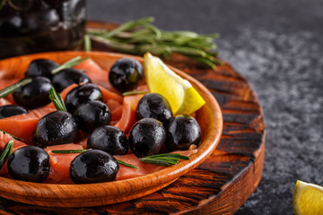 Salmon with olives and lime on a wooden board.