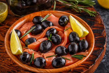 Salmon with olives and lime on a wooden board.