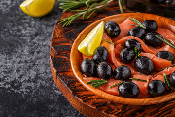 Salmon with olives and lime on a wooden board.
