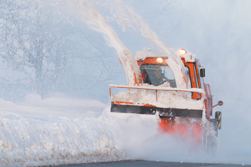 Snow truck cleaning snow from the road and streets working at sunset light on snowy day