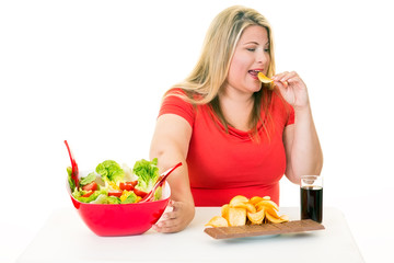 Woman pushing away salad and eating junk food.