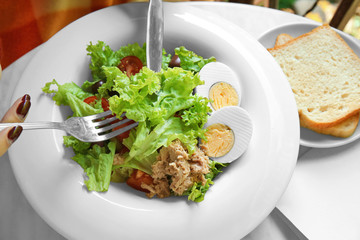 Woman eating tasty salad in cafe