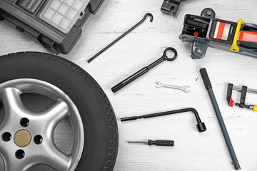 Car wheel with tools on wooden background
