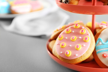 Stand with colourful Easter cookies on kitchen table, closeup