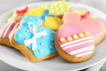 Plate with colourful Easter cookies on kitchen table, closeup