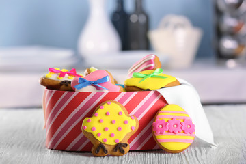 Box with tasty Easter cookies on kitchen table