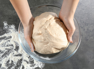 Female hands with raw dough on kitchen table