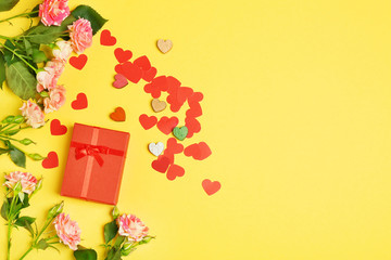 Gift box, flowers and decorative hearts on color background