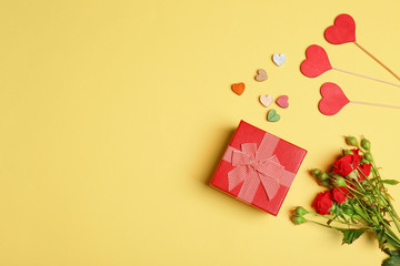 Gift box, flowers and decorative hearts on color background