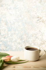 Tea cup with tulips on the wooden table opposite beautiful natur