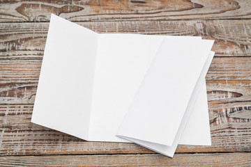 Trifold white template paper on wood texture .