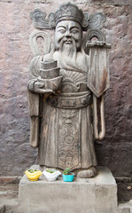 Traditional Chinese statue closeup against a background of clay wall