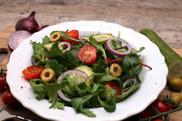 Caprese. Caprese salad. Italian salad. Mediterranean salad. Italian cuisine. Mediterranean cuisine. Tomato mozzarella basil leaves black olives and olive oil on wooden table. Recipe - Ingredients