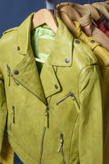 Many colored  leather jacket hanging on rack on blue background