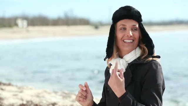 femme qui met une chapka sur la plage en souriant