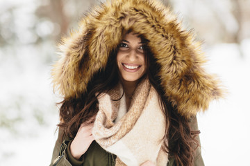 Young woman with a fur hood in the park on the snow