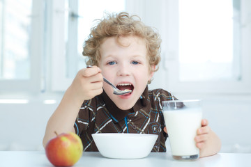 Boy eating cereal while having breakfast  in the kitchen.