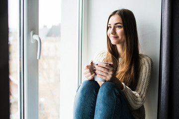 Young beauty woman drink coffee near window at home
