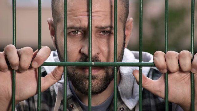  sad and frustrated man behind bars