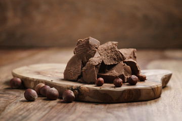 chunks of gianduja with hazelnuts on wood board, premium chocolate dessert