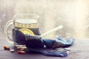 hot drink for convalescence/ infusion lemon in the transparent mug beside thermometer and tablets...
