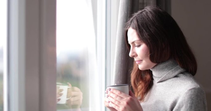 Woman looking out of window with morning coffee