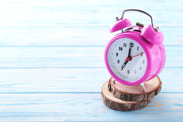 Pink alarm clock on blue wooden table
