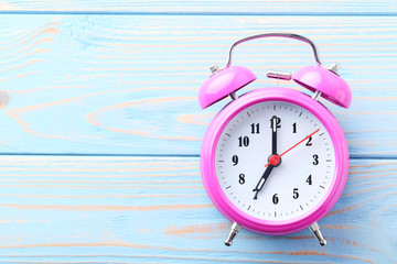 Pink alarm clock on blue wooden table