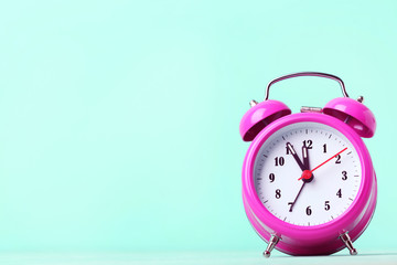 Pink alarm clock on a green background