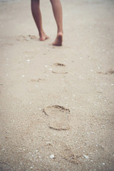 Young woman walking on the beach with barefoot.