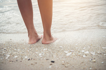 Young woman standing on the beach with barefoot.