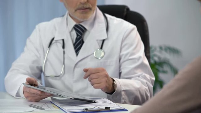 Doctor typing patient's data on tablet, keeping medical records, consultation