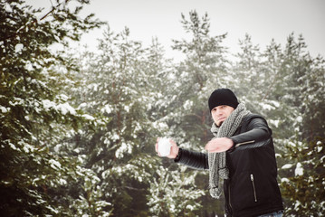 A young man throwing a snowball in the forest