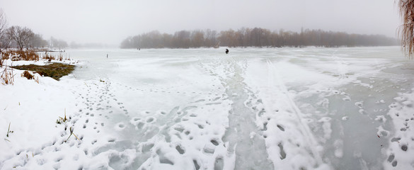 panorama of a frozen river foggy winter day. 