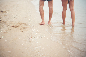 Rear of Young couple walking on the beach with barefoot.