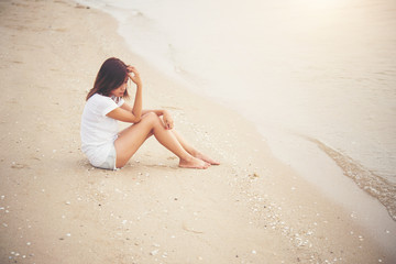 Fototapeta na wymiar Young woman with looks lonely feel sit on the beach. Sad woman a
