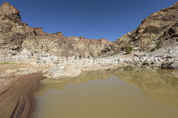 Wandergruppe überquert den Fish River auf Felsbrocken