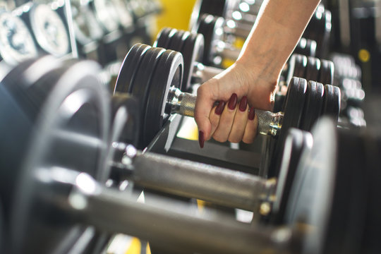 Close up of woman's hand holding dumbbell in gym.