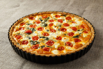 Vegetarian homemade pie, Quiche with tomatoes, spinach and feta cheese.