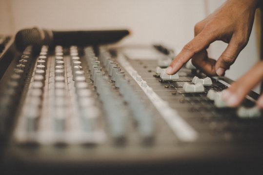 Man hands of sound engineer adjusting audio mixing console.