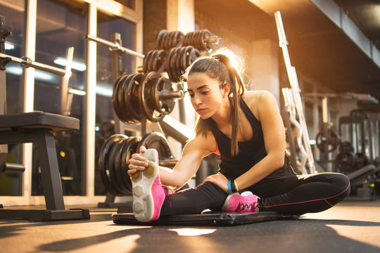 Young Woman Stretching Legs In Gym.