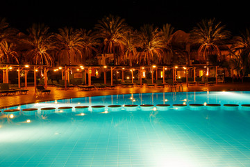 illuminated pool at night with tropical palms