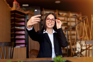 Beautiful young woman taking selfie at cafeteria.