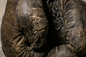 Naklejka premium old boxing gloves hang on nail on texture wall