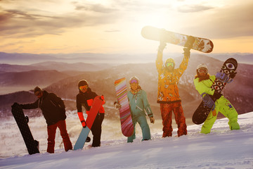 Group of friends snowboarders having fun on the top of mountain