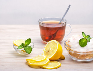 Завтрак,чашка чая с лимоном и мятой,пирожное на тарелке.