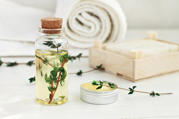 Thyme oil skincare. Bottle of herbal extract, aromatic fresh green twigs, facial cream sample jar,...